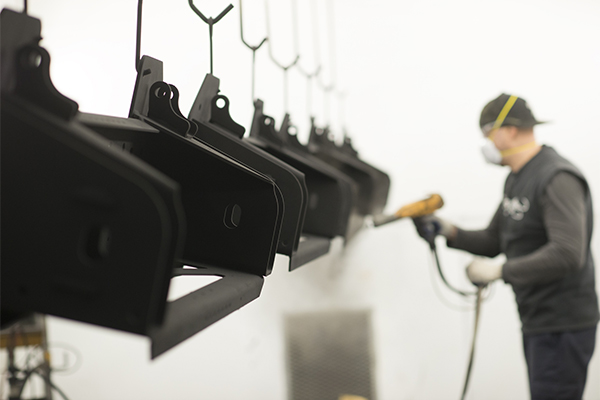 An employee powder coating a customers items